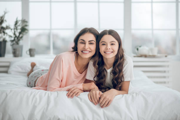 istock Similar mom and daughter lying on stomachs on bed 1305514201
