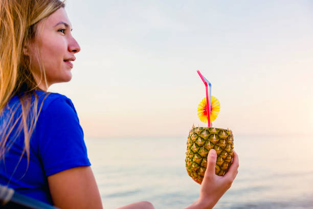 istock Woman with pineapple cocktail on the beach 1305514262