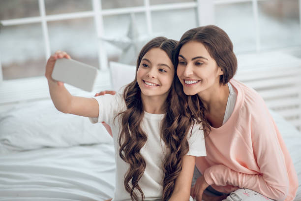 istock Daughter with mom taking selfie on smartphone 1305514299