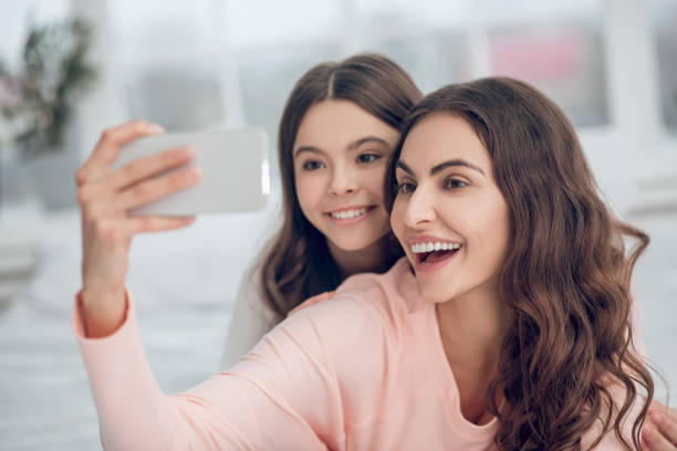 istock Beautiful mother with smartphone taking selfie with daughter 1305514306