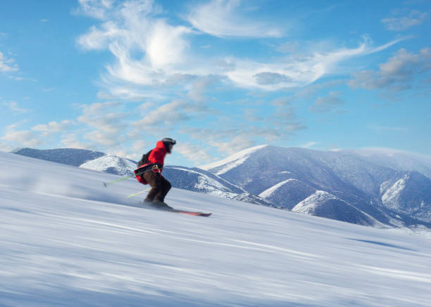 Happy person in red jacket skiing down slope stock photo