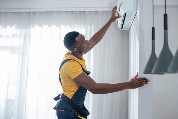 istock Service man in yellow tshirt looking busy while installing the air-conditioner 1305517058