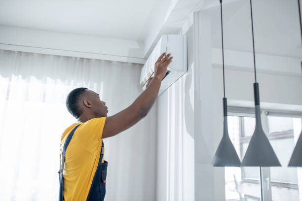 istock Dark-skinned service man in yellow tshirt installing the air-conditioner 1305517065