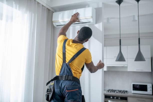 istock Service man in yellow tshirt looking busy while installing the air-conditioner 1305517070
