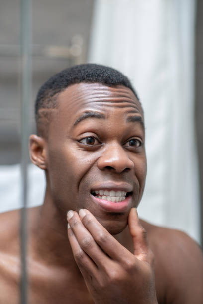 istock African american short-haired guy looking at himself in the mirror 1305517386