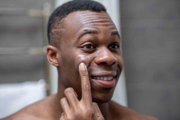 istock African american short-haired guy applying some cream on his face 1305517399