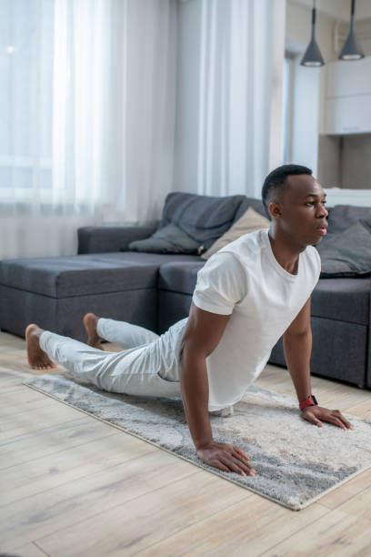 istock African american guy in white clothes having ahome workout 1305517416