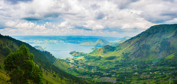 Lake Toba and Samosir Island view from above Sumatra Indonesia. Huge volcanic caldera covered by water, traditional Batak villages, green rice paddies, equatorial forest. Lake Toba and Samosir Island view from above Sumatra Indonesia. Huge volcanic caldera covered by water, traditional Batak villages, green rice paddies, equatorial forest. danau toba lake stock pictures, royalty-free photos & images