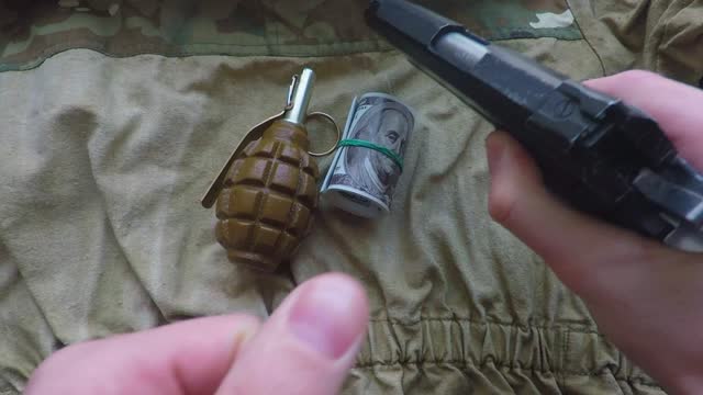 pistol and a hand grenade are placed on the camouflage