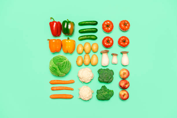 Vegetables and fruits symmetry, isolated on a colored background, top view. Healthy food concept Creative layout with fresh vegetables and fruits, isolated on a green background. Flat lay with healthy food aligned on a tabletop. Vegan groceries. carrot isolated vegetable nobody stock pictures, royalty-free photos & images