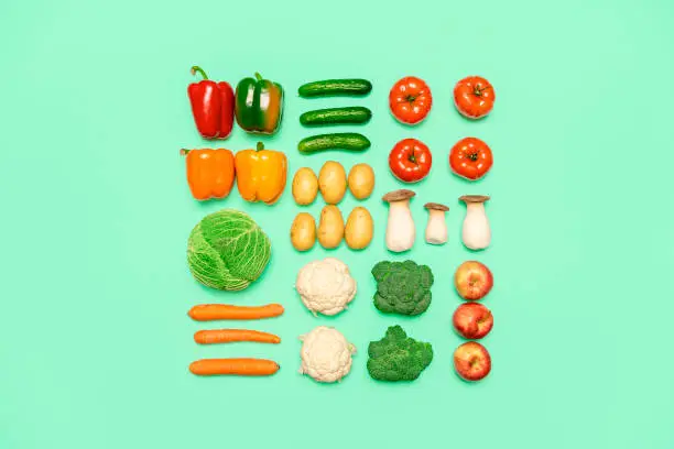 Photo of Vegetables and fruits symmetry, isolated on a colored background, top view. Healthy food concept