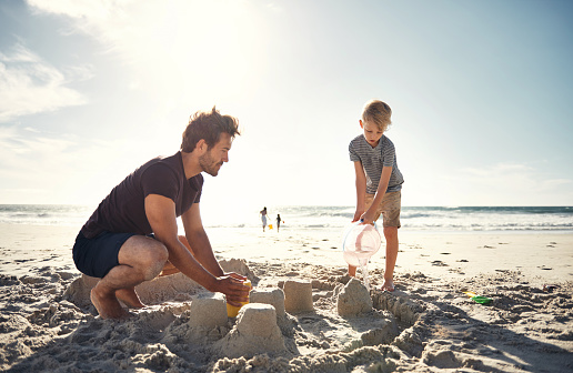 Shot of a man building sandcastles with his son on the beach