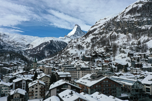 Zermatt the swiss mountaineering and ski resort with a population of 5,800 inhabitants captured during winter season. The image shows nearby the whole town with the famous landmark Matterhorn in the background.