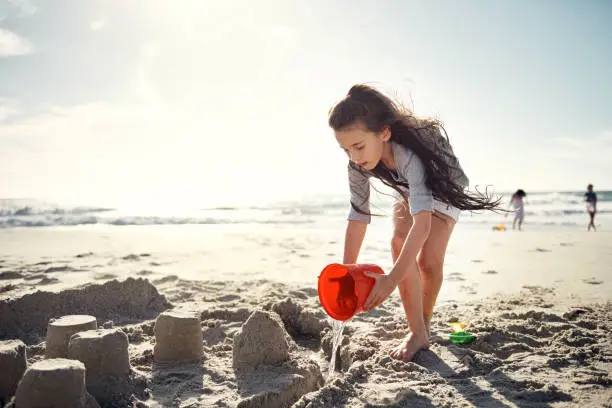 Shot of a little girl building sandcastles on the beach