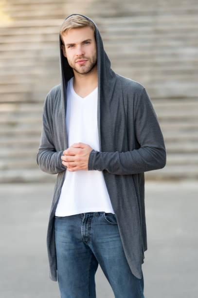 comfortable clothes daily wear. great taste to dress well. male fashion influencer. fashionable young model man. street style outfit. handsome man with hood standing urban background. fashion trend - fashion men fashion model male imagens e fotografias de stock