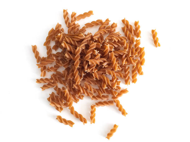 veduta aerea di bunch di maccheroni sotto forma di spirali da vicino. manciata di pasta fusili a pasta fusili integrale isolata su sfondo bianco. concetto di pasta e proteine. modello alimentare sano. - cereal plant processed grains rice wheat foto e immagini stock