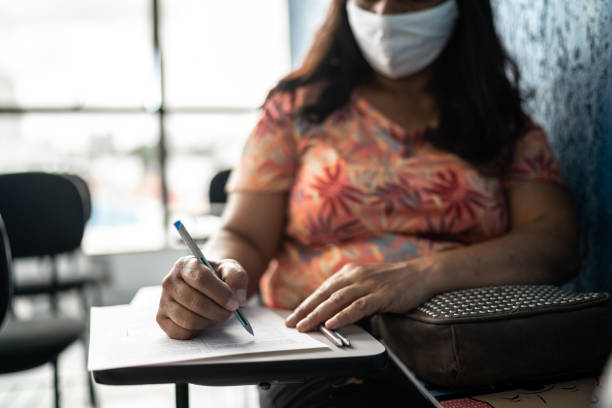 istock Female student taking notes or taking a test in a university - wearing face mask 1305527481