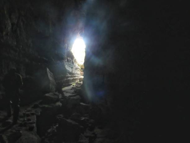 istock Dark cave being lit by the sunlight coming from one of its openings 1305529012