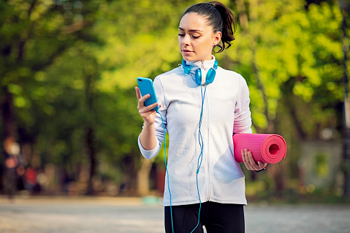 Young woman is looking her mobile phone after exercises in a park