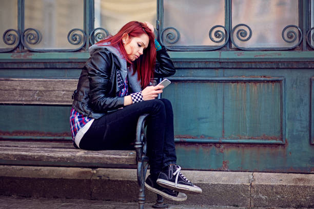 istock Depressed young woman is looking her mobile phone 1305534646