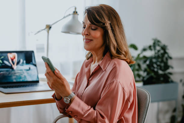 istock Working from Home: a Beautiful Happy Senior Woman Using her Smartphone at her Home Office 1305535851