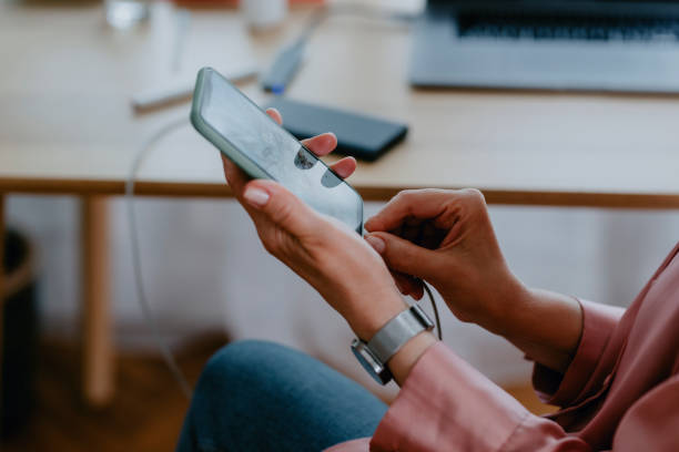 Hands of an Anonymous Woman Connecting a Power Bank to her Smartphone Unrecognizable woman charging her mobile phone at home, a close up phone charger cable stock pictures, royalty-free photos & images