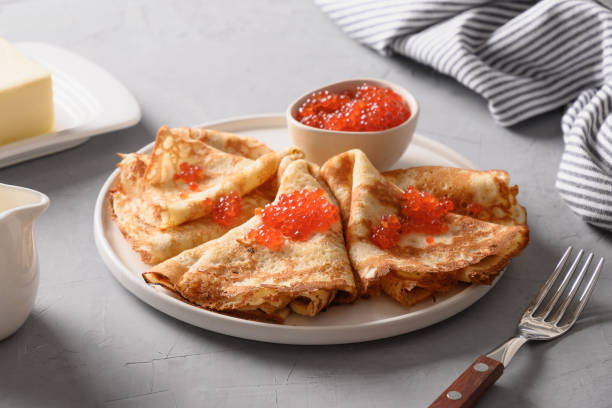 istock Russian thin pancakes or blini with red caviar on grey. 1305536471