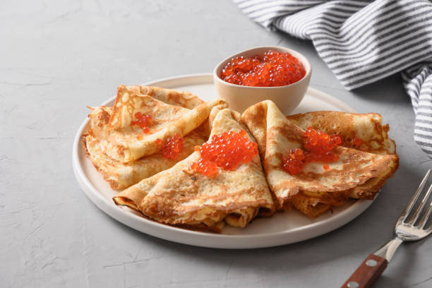 istock Russian thin pancakes or blini with red caviar on grey. 1305536478