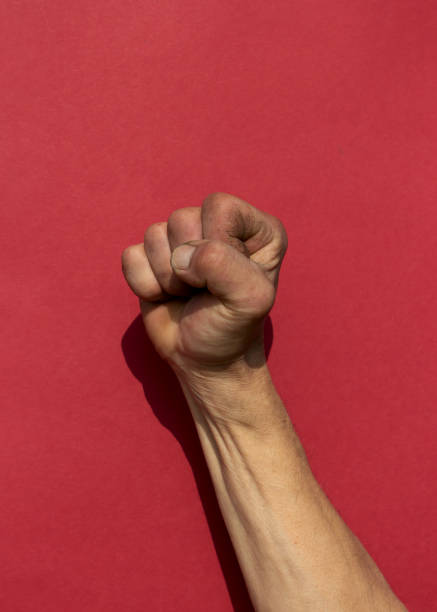 swarthy szorstka ręka mans z zaciśniętą pięścią na czerwonym tle. cesar chavez koncepcja dzień. - mexican american zdjęcia i obrazy z banku zdjęć