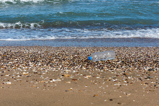 A discarded plastic water bottle is washed up on a sandy beach