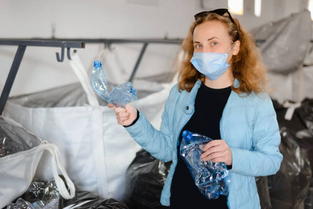 istock Young red-haired girl sorts plastic bottles. Separate garbage concept 1305542024