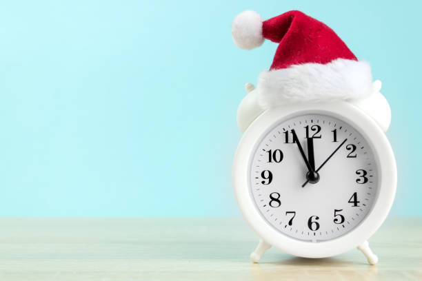 istock White alarm clock with red santa cup on wood table with blue background. 1305542163