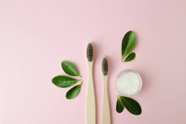 istock Eco-friendly bamboo toothbrushes, dentifrice and green leaf on pink background. 1305543003