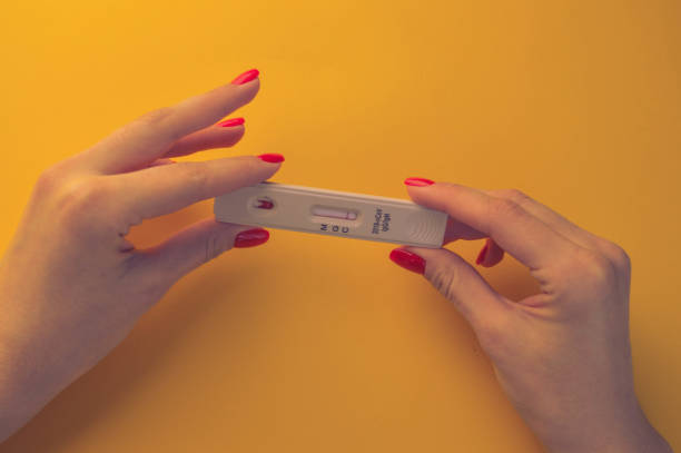 test for coronavirus on an orange background. medical analysis. girl with bright red manicure holding a test for antibodies to coronavirus test for coronavirus on an orange background. medical analysis. girl with bright red manicure holding a test for antibodies to coronavirus. diabetes epidemiology stock pictures, royalty-free photos & images