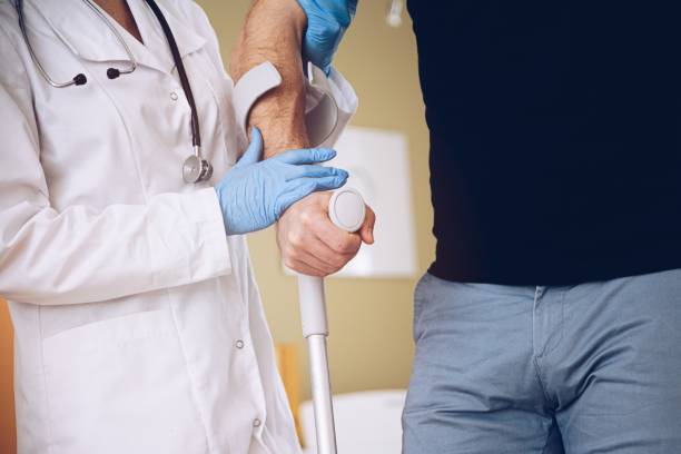 istock Female doctor supporting young man walking on crutches. 1305544457