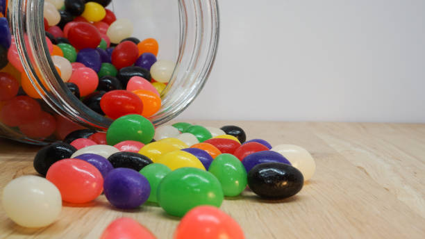 Jelly beans spilling out of a glass jar Jelly beans spilling out of a glass jar. Copy space in top corner of image jellybean photos stock pictures, royalty-free photos & images
