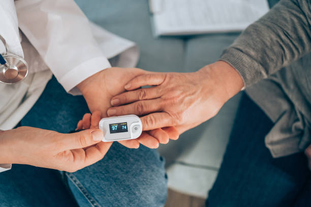 Female doctor at home visit. Doctor examining mature woman using oximeter at home. o2 stock pictures, royalty-free photos & images