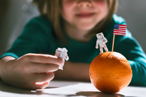 Happy child playing an astronaut Happy boy playing an astronaut. He uses an orange as a planet or a Moon. Landing on the Moon. Hand-painted American flag. apollo 11 stock pictures, royalty-free photos & images