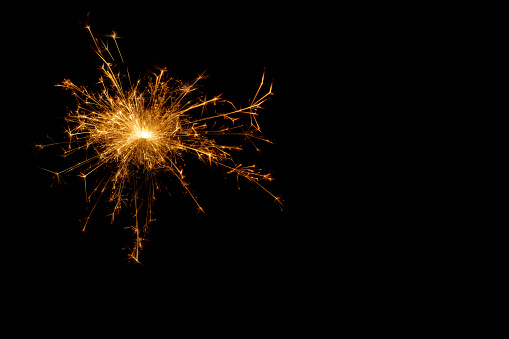A picture of a real sparkler set alight and isolated against a black background