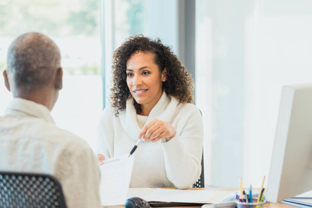 istock Female bank manager explains loan document to unrecognizable mature man 1305552407