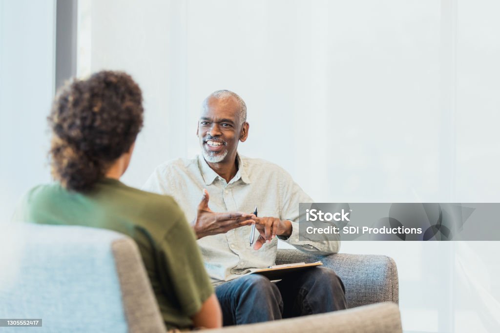Unerkennbare Frau hört als fröhliche Ratgebergesten zu und spricht - Lizenzfrei Psychosoziale Beratung Stock-Foto