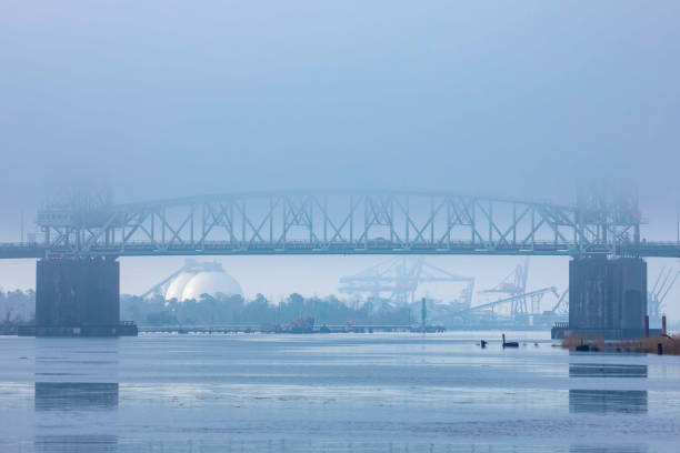 Industrial Bridge Over River with Fog The Cape Fear Memorial Bridge in Wilmington, NC enveloped in the morning fog cape fear stock pictures, royalty-free photos & images