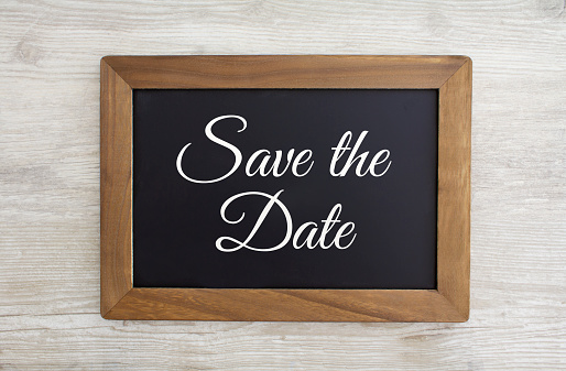 Save the Date written on a black chalk board with a wooden frame, stock photo.