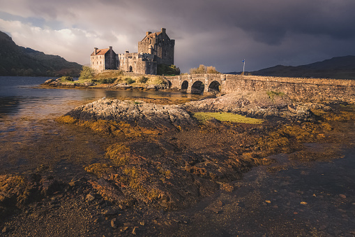 Moody, dramatic light and shadow on the historic Eilean Donan Castle near the village of Dornie in the Western Scottish Highlands, Scotland.