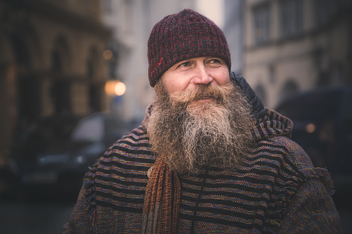 Portrait of a local cheery Czech street vendor with a long beard and winter hat in Prague, Czech Republic.