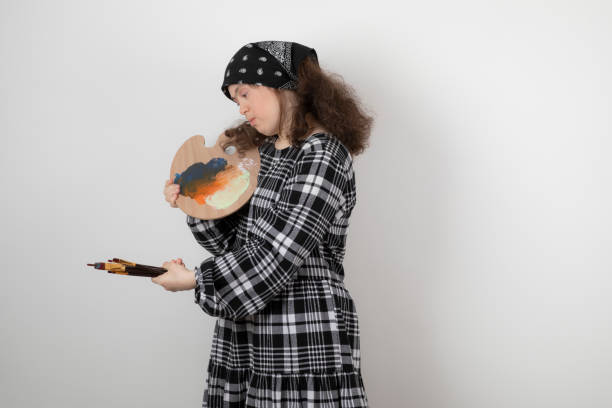 istock Adorable young girl with down syndrome looking at painter palette 1305563705