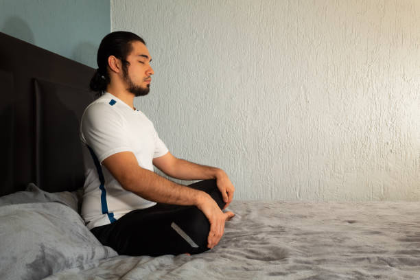 그의 침대에서 요가와 명상을 연습 하는 스포츠웨어와 젊은 히스패닉 남자 매우 조용하고 평화로운 - mantra 뉴스 사진 이미지