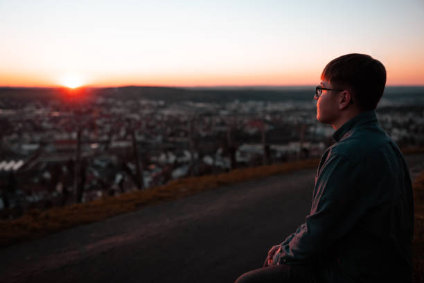 istock Young man standing on hill top enjoying the sunset 1305566382