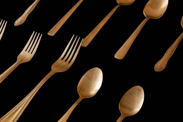 istock shiny spoons and forks on a black background 1305573090