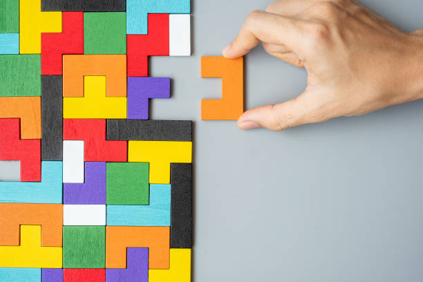 istock hand connecting geometric shape block with colorful wood puzzle pieces. logical thinking, business logic, Conundrum, decision, solutions, rational, mission, success, goals and strategy concepts 1305574970